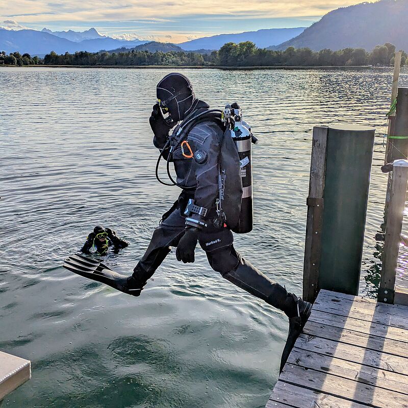 Taucher Manfred K. springt von Holzsteg in Bergsee, Vorarlberg