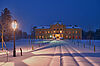 Am Bild ist das verschneite Schloss Eckartsau bei Nacht zu sehen. Im Vordergrund eine helle Laterne.