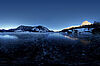 Der vereiste Grundlsee in der Dämmerung, im Hintergrund Bergpanorama, teilweise schon mit Sonne bedeckt.