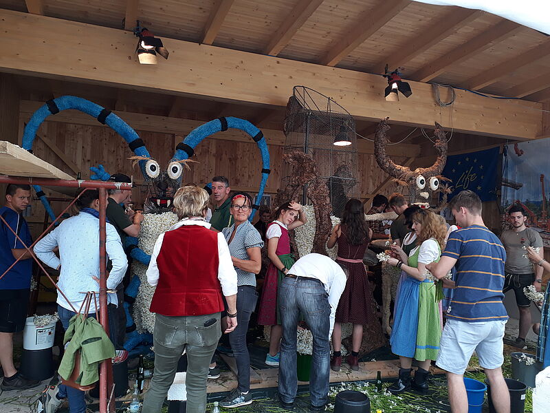 Viele Personen stehen um die Drahtgestellfigur herum und stecken Narzissen.