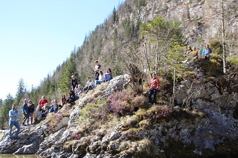 Viele SChülerinnen und Schüler sitzen auf einem Felsen und posieren für ein Gruppenfoto.