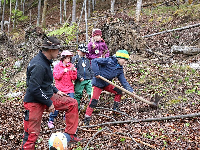 ÖBf-Waldpädagoge Martin Steyrer und Schüler*innen beim Einpflanzen der Jungbäume (c) Ferienregion Dachstein Salzkammergut