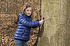 Kind legt Stethoskop an Rinde der Rotbuche an um dem Inneren des Baumes zu lauschen.