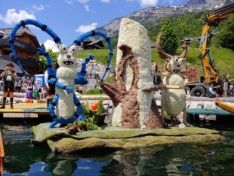 Die Figur schwimmt auf einem Floß am Uferrand.